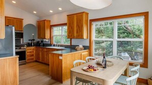 Een moderne keuken met houten kastjes, een centraal eiland en een eethoek met een tafel en stoelen.