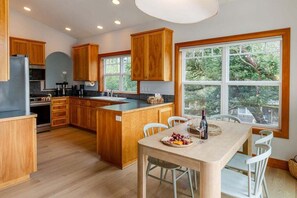 Eine moderne Küche mit Holzausstattung, einer zentralen Kochinsel und einem Essbereich mit Tisch und Stühlen.