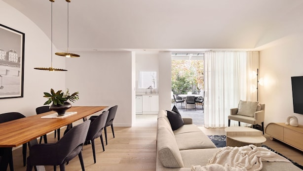 Una sala moderna con comedor, un sofá, una mesa de centro y un televisor.