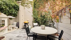 A patio with a round table and chairs, a barbecue grill, and a covered seating area. - Ivy Terrace, Annandale IH (Annandale)