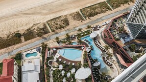 Et resort med flere swimmingpools, liggestole og en strand.