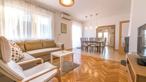 Un salon moderne comprenant un canapé, un fauteuil, une table à manger et un téléviseur.