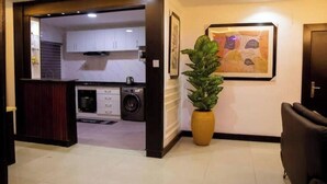 A modern interior with a kitchen, a potted plant, and a framed artwork on the wall. - The Luxe Stay, 2 Bed Room Apartment (Lagos)