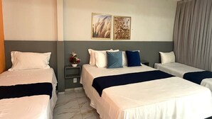 A hotel room with two beds, a nightstand with a vase, and two wall-mounted pictures.
