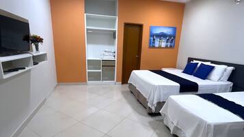 A hotel room with two beds, a TV, a wardrobe, and a painting on the wall.