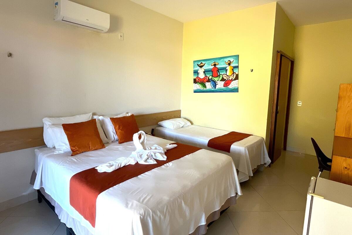 Habitación de hotel con dos camas, un cuadro en la pared y un equipo de aire acondicionado.