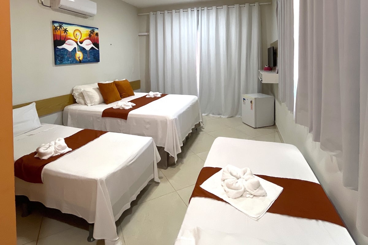 Habitación de hotel con dos camas, un cuadro en la pared, un televisor y un refrigerador pequeño.