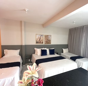 A hotel room with two single beds, a large window with curtains, a small table, and a wall-mounted light fixture. - Pousada Bugaendrus Paradise (Touros)