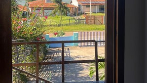 A view through a window of a building with a tiled roof, a fenced outdoor area, and a clear sky.