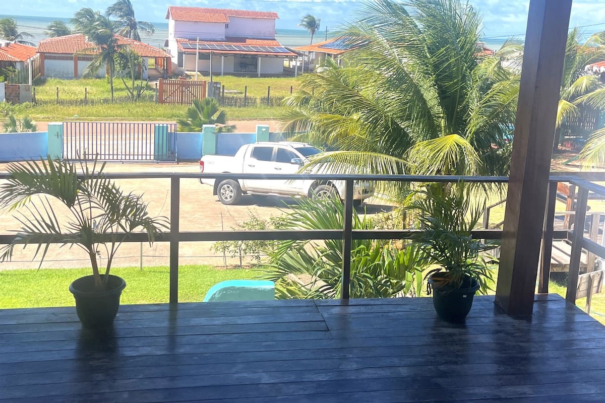 Un espacio al aire libre cubierto con vista a casas, una camioneta estacionada y palmeras.