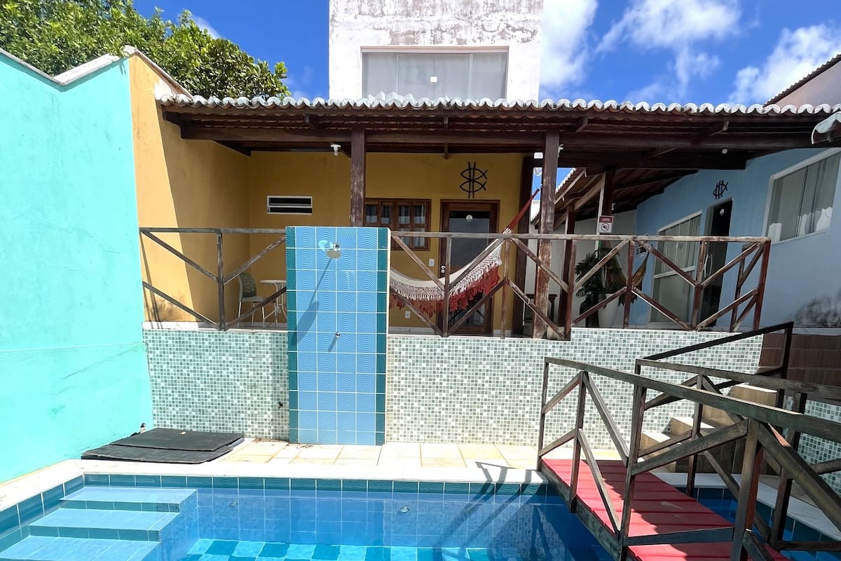 Una piscina con azulejos azules, una hamaca y una escalera que lleva a un edificio con una puerta marcada con un signo de dólar.