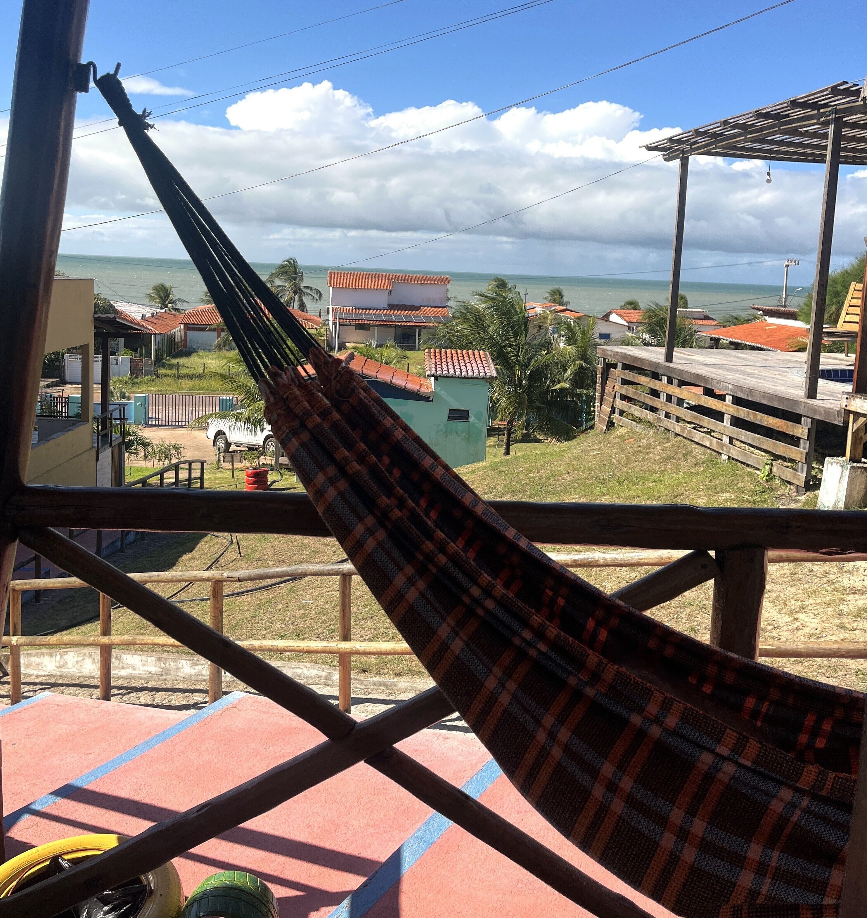 Uma rede em um quarto com vista para o mar e edifícios.