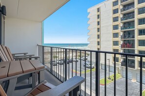 A balcony with a view of the ocean, a parking lot, and a multi-story building. - Island Winds East 311 | Walk to the Hang Out | Beachview | My Beach Getaways (Gulf Shores)