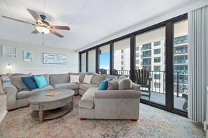 Ein modernes Wohnzimmer mit einem Ecksofa, einem Couchtisch und einem Deckenventilator.