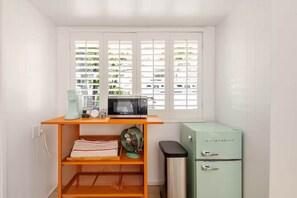 A compact kitchen with a microwave, a small fridge, and a window with blinds. - 90210 NEST: Private Pool Retreat in Beverly Hills (Beverly Hills)