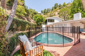 A swimming pool with a fence, a chair, and a house in the background. - 90210 NEST: Private Pool Retreat in Beverly Hills (Beverly Hills)