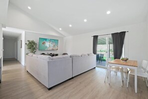 A modern living room with a sofa, a dining table, and a TV. - Spacious 4 Bedroom House W/ Amazing Backyard (Chula Vista)