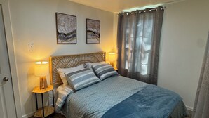 Een slaapkamer met een bed, twee wandlampen, een deur en een raam met gordijnen.