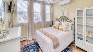 Ein Schlafzimmer mit Bett, Deckenventilator, Kleiderschrank und einem Fenster mit Vorhängen.