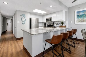 A modern kitchen with white cabinets, a marble island, and a 'Gather' sign. - Cozy 3-bedroom condo with Ocean view and AC in delightful Myrtle Beach (Myrtle Beach)