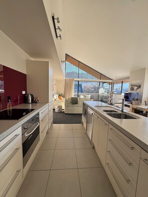 A modern kitchen with a large island, integrated appliances, and a view to the living area. - Luxury Corner Apartment In Central Hanmer
Springs. (Hanmer Springs)