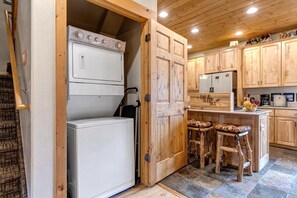 A kitchen with wooden cabinets, a built-in washer and dryer, and a bar stool area. - KBM Resorts | Timber Wolf Lodge | Mountain Elegance with Gas Fireplace, Common Hot Tubs, Near Canyons Village! TWL-5b (Park City)