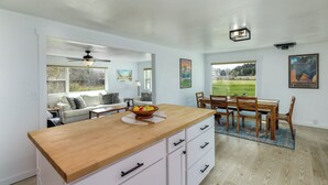 Una cocina moderna con encimera de madera, armarios blancos y un comedor con mesa y sillas de madera.