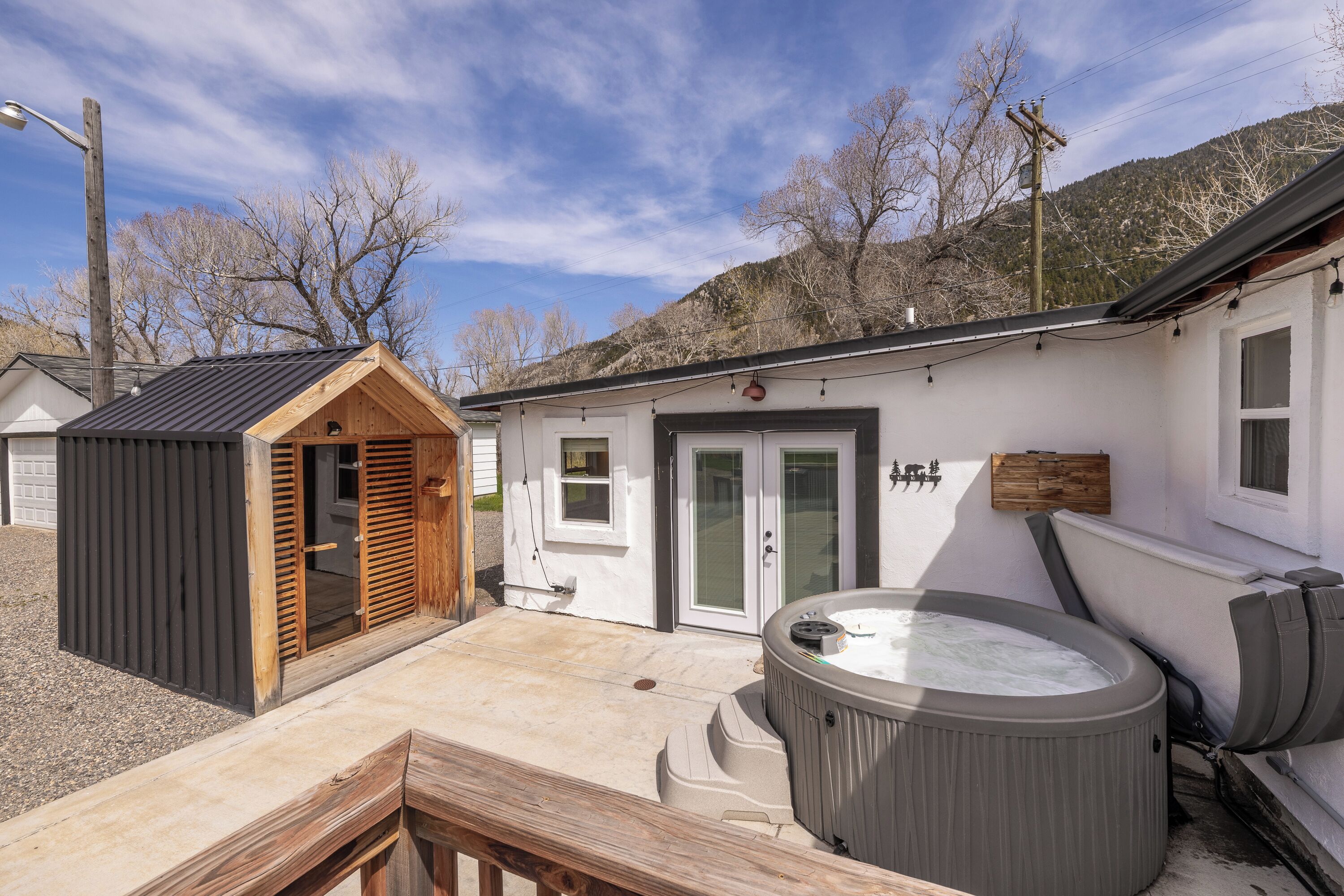 Un espace bien-être comprenant un jacuzzi, une terrasse en bois et une petite structure en bois.