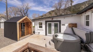 Un área de spa con un jacuzzi, terraza de madera y una pequeña construcción de madera.