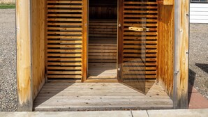 Una estructura de madera con una puerta de listones y una ventana pequeña, asentada sobre una base de hormigón.