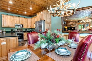 A rustic kitchen with wooden cabinets, stainless steel appliances, and a dining area with leather chairs and a chandelier. - KBM Resorts | Timber Wolf Lodge | Walk to Canyons Cabriolet, Fireplace, BBQ, Aspens and Creek, Parking! TWL-12c (Park City)