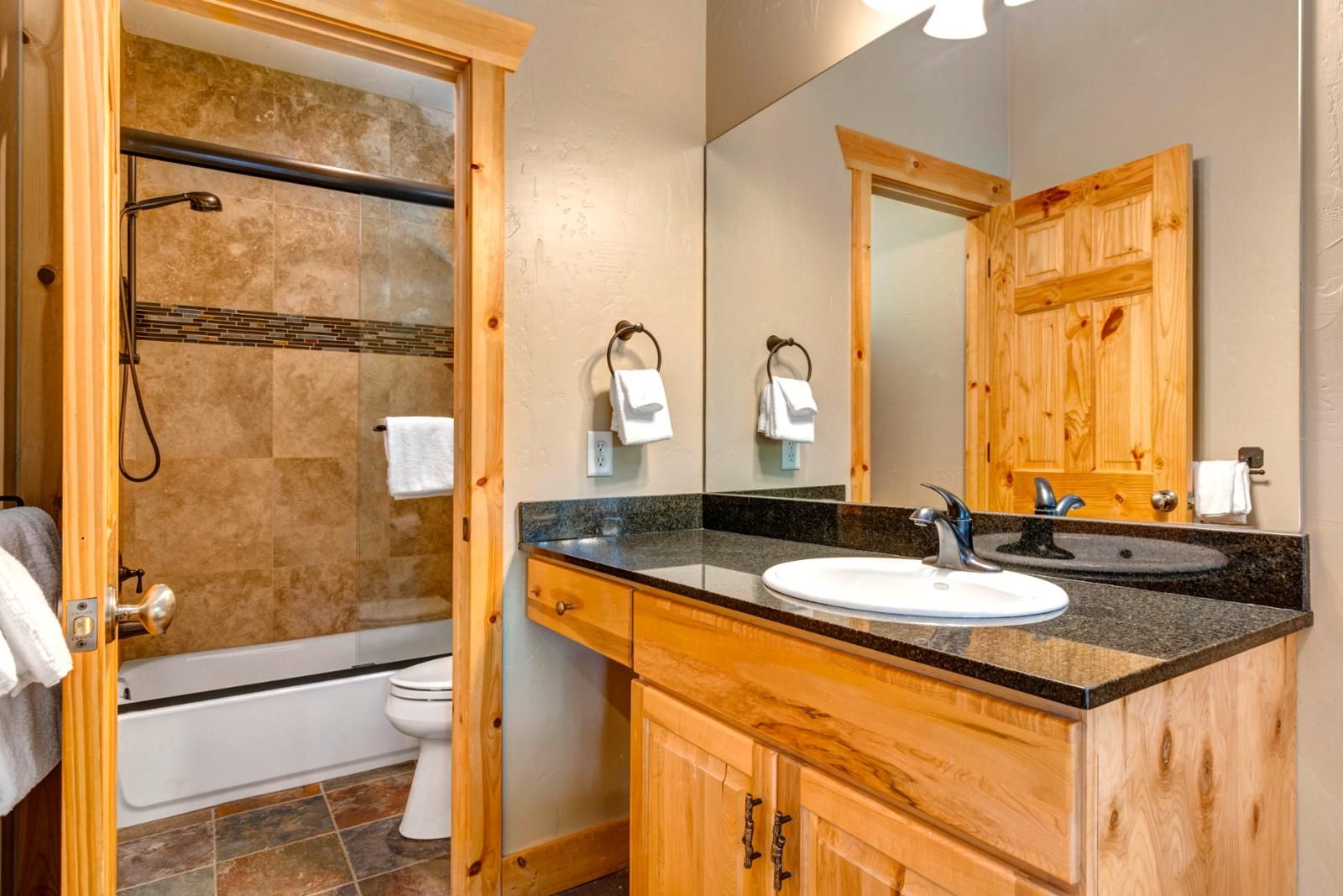 Een moderne badkamer met een douche, toilet en wastafel met een wasbak en spiegel.