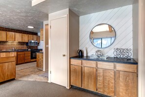 A modern kitchen with wooden cabinets, a built-in microwave, and a countertop with a coffee maker and decorative items. - KBM Resorts | In the Heart of Park City, Walk to Slopes, Summer A/C, Spacious, Private Dry Sauna! STR-1 (Park City)