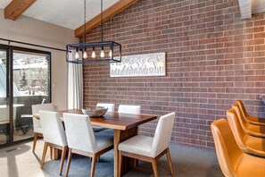 A dining area with a brick wall, a wooden table, and four chairs. - KBM Resorts | In the Heart of Park City, Walk to Slopes, Summer A/C, Spacious, Private Dry Sauna! STR-1 (Park City)