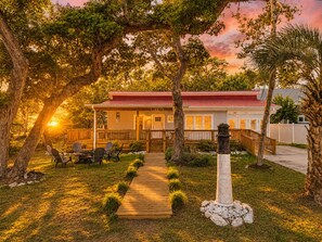 Ein Haus mit Veranda, Sitzgelegenheit im Freien und einem Weg zum Eingang.
