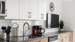 Een moderne keuken met witte kasten, een roestvrijstalen spoelbak en een koffiezetapparaat.
