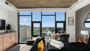 Een moderne hotelkamer met een groot raam, een flatscreen televisie, een bureau en een comfortabele zithoek.