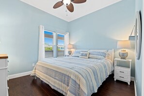 A bedroom with a bed, two bedside tables with lamps, a ceiling fan, and a window with blinds. - Lucy's Gift: Spacious balcony overlooking the intercoastal waterway (Southport)