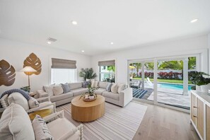 Ein modernes Wohnzimmer mit einer Sofagarnitur, einem Couchtisch und Blick auf einen Swimmingpool.