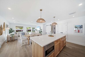 Una cocina moderna con una isla central, armarios de madera e iluminación colgante.