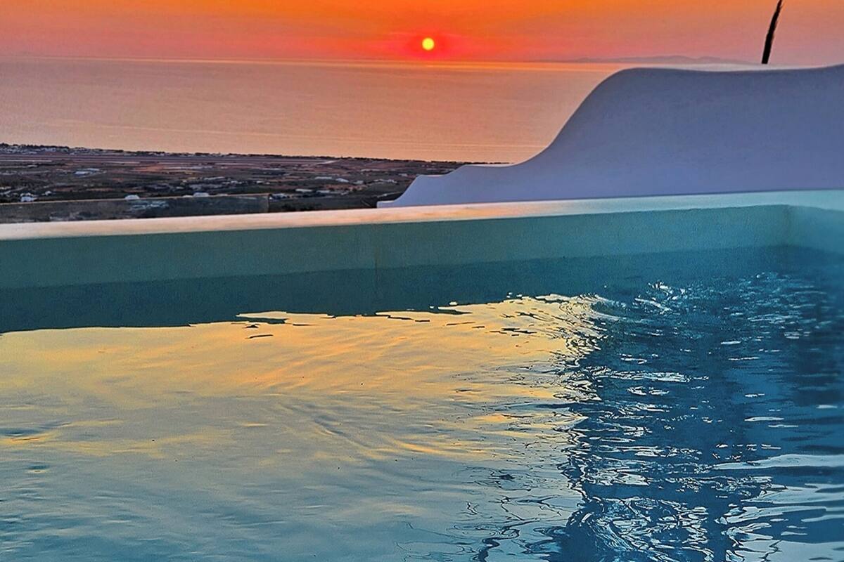 Une vue sur le coucher de soleil depuis une piscine à débordement, avec une vue sur la ville en arrière-plan.