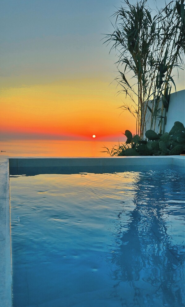 A swimming pool with a sunset view, calm water, and a distant horizon. - Martynou View (Santorini)