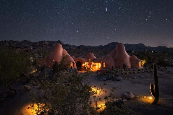 A desert landscape with unique, rounded-roof structures illuminated at night.