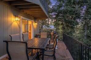 An outdoor deck with a table and chairs, a railing, and a view of trees. - Lakeview Lodge,HotTub, FirePit, BBQ, firework view (Big Bear Lake)