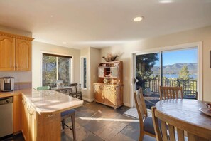 A kitchen with a large island, a dining area with a table and chairs, and a view through a sliding glass door. - Lakeview Lodge,HotTub, FirePit, BBQ, firework view (Big Bear Lake)