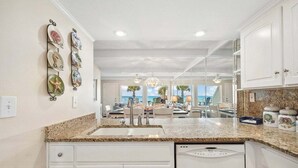 A kitchen with white cabinets, granite countertops, and a view to the outside. - Gulfside Gem 144-Gulf Views-Sleeps 6 (Panama City Beach)