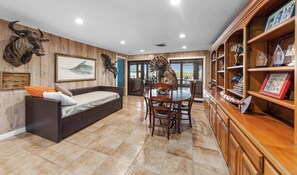 A room with a bed, a dining table with chairs, a wooden cabinet with awards, and a wall-mounted bird sculpture. - Casa Arroyo First Floor - Pier, Game Room (Arroyo City)