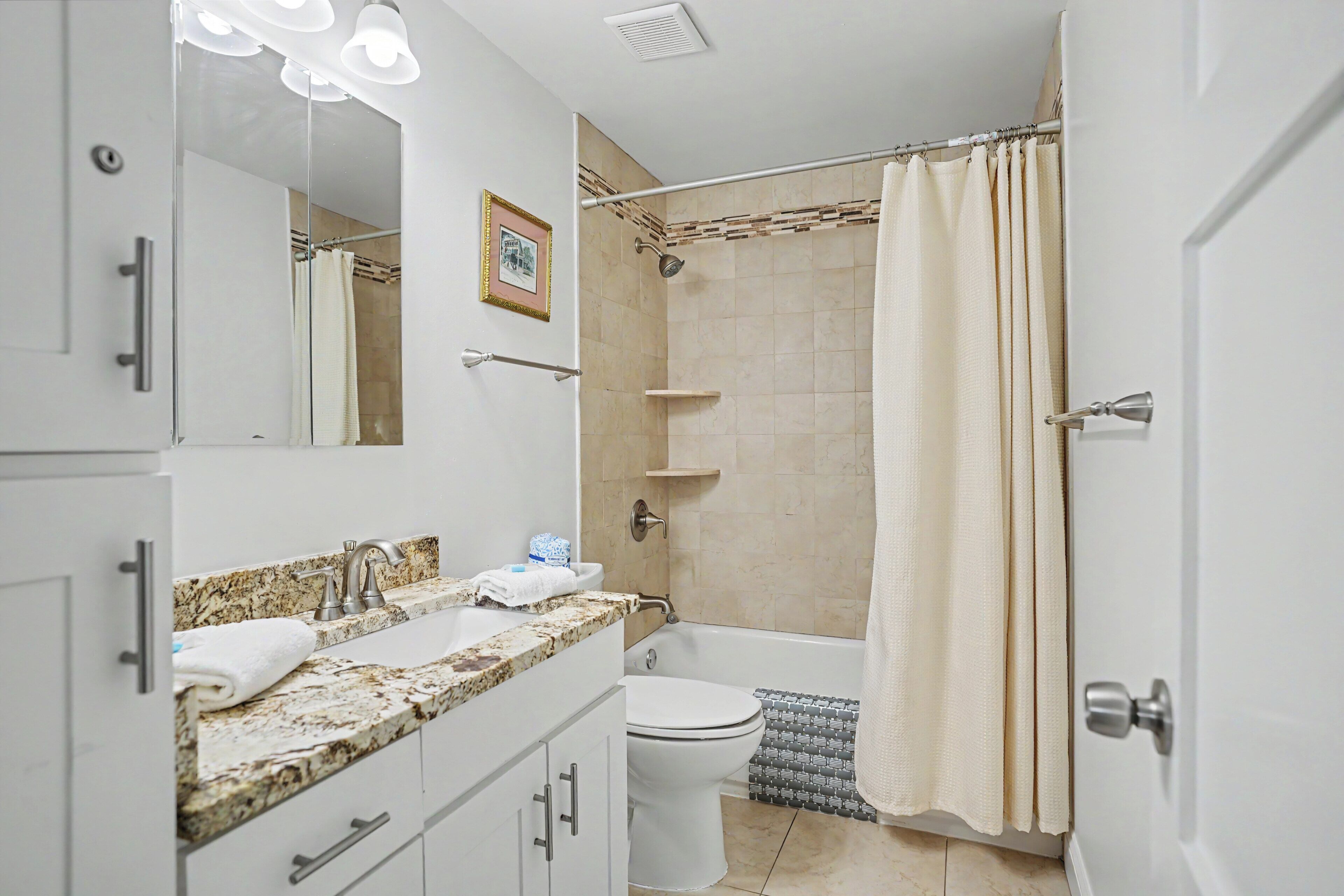 A bathroom with a sink, mirror, shower, and toilet.