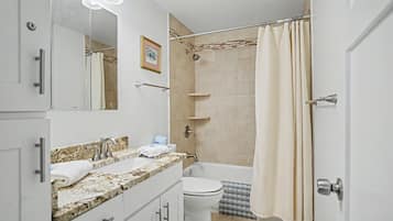 A bathroom with a sink, mirror, shower, and toilet.