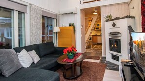 A living room with a sofa, a coffee table with a red flower vase, a fireplace, and a staircase leading to an upper level.